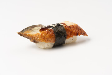 Sushi nigiri unagi. Eel slice with boiled rice, nori, sesame seeds and teriyaki sauce on a white plate.