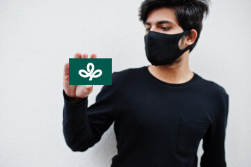 Japanese man wear all black with face mask hold Miyagi flag in hand isolated on white background....