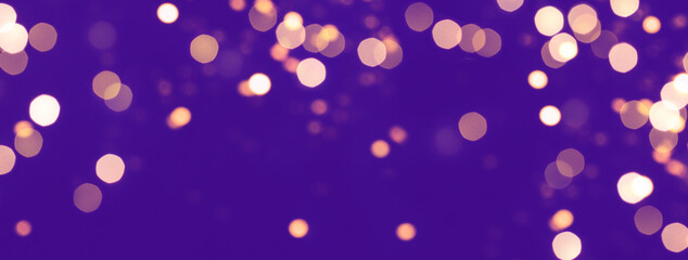 Festive abstract banner with golden bokeh lights on violet background