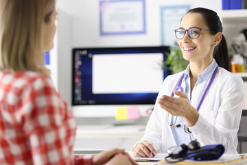 Smiling doctor talking to patient at table in clinic
