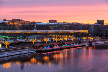 View of Zaryadye Park with soaring bridge, Moscow river with reflection in the water at dawn on new year and Christmas holidays. Moscow, Russia