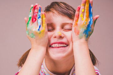 Funny portrait of realy happy beautiful young child girl with  painting colorful hands.
