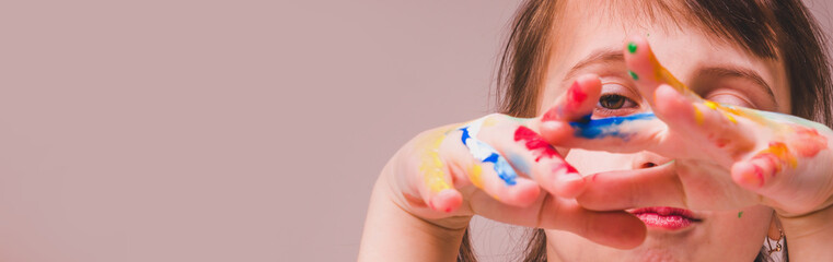Close up beautiful young girl with colorful painting hands. Selective focus on eye. Copy space for design.