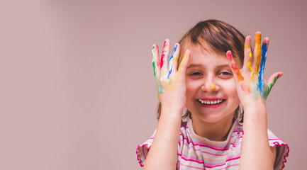 Really happy beautiful young girl with children's makeup and painting colorful hands. Copy space for design.