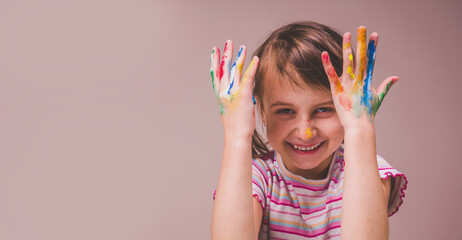 Portrait really happy beautiful young child girl with children's face makeup and painting colorful hands. Copy space for design.