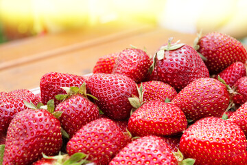 A container full of fresh ripe strawberries on a wooden table.