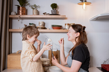 Cooking together concept. Mom and son having fun while decorating layered carrot cake in the...