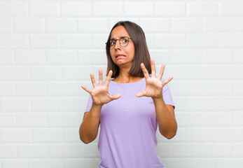 latin woman feeling terrified, backing off and screaming in horror and panic, reacting to a...
