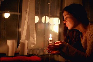 girl at the window dreams in winter evening / the romance of candle, the beautiful model in Christmas evening dreams