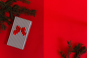 Fototapeta premium New year's gift on a red background. Merry Christmas and happy New year. Colorful bright design. Black and white gift packaging.Christmas background top view, flat layout, banner, postcard, copy space
