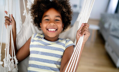 Adorable girl enjoying on indoor swing in living room
