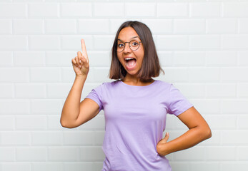 latin woman feeling like a happy and excited genius after realizing an idea, cheerfully raising...