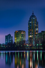 Night view of modern buildings in the Obolon district of Kiev, Ukraine, close to the Dnieper River, The lights reflect on the calm water.