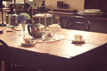 Retro photo of traditional tea accessories served on a wooden table in the kitchen. Toned image.