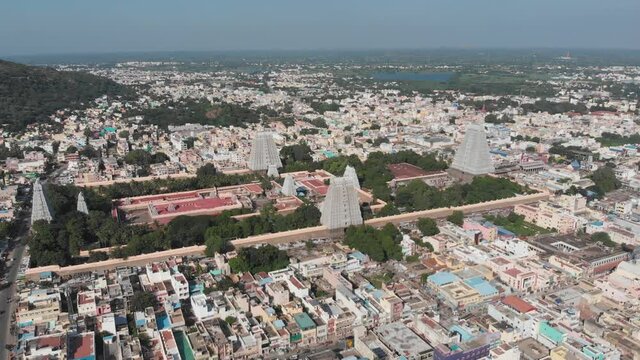 Static aerial shot of Hindu Religion Temple in Tiruvannamalai during daytime with cityscape and lake in background.