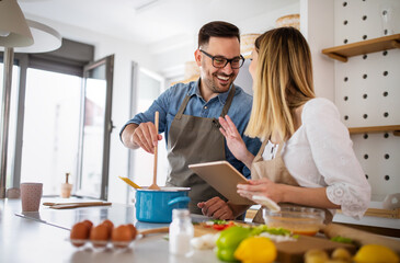 Happy young couple enjoys and having fun preparing healthy meal together at home kitchen.
