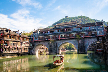 the river, the boat, stone bridge and the old houses at ancient phoenix town in the morning at...
