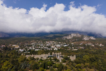 Fototapeta na wymiar Aerial drone photo of Vorontsov palace, huge green famous garden against the mountains hidden in fog in sunny day, sightseeing in the Crimea