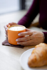 Fototapeta na wymiar A girl has a croissant for Breakfast in a cafe