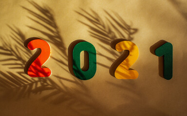 Wooden multi-colored numbers 2021 on a beige background with beautiful shadows from the Christmas...