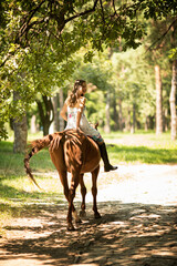 Girl with a long brown hair and tall boots rides a horse.