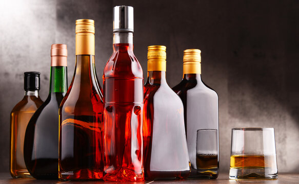 Glass and bottles of assorted alcoholic beverages.