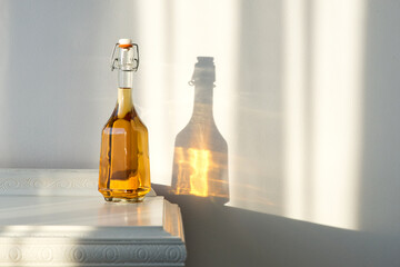 Elegant bottle with alcohol and empty glass over a vintage cabinet and a beautiful sun reflection...