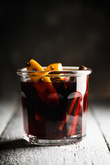 Mulled red wine with oranges and different spices in glass on the rustic background. Christmas food. Winter decorations. Selective focus. Shallow depth of field.