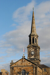 Fototapeta na wymiar Old Rural Stone Church with Spire & Clock against Blue Sky 
