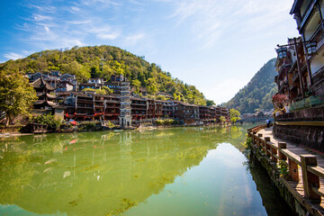 the river, the boat, stone bridge and the old houses at ancient phoenix town in the morning at...