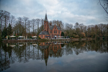 Fototapeta premium Bar restaurante con forma de castillo al borde de lago del amor o Minnewater en Brujas. belgica.