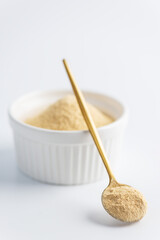 Sunflower lecithin in a bowl and spoon on a white background.