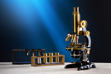 Rechts stehendes Vintage altes Mikroskop auf dem Tisch mit blauem Hintergrund