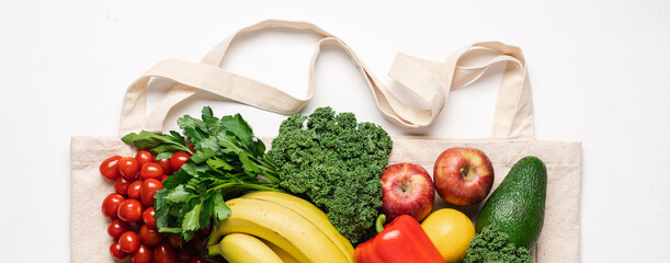 Cotton bag full of vegetables and fruits. Closeup shopping bag on white background. Zero waste buying