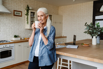 Happy senior woman holding cup of tea while standing