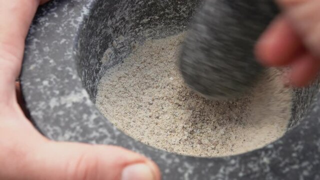 Super close-up of pestle mixing spices in the grey stone mortar