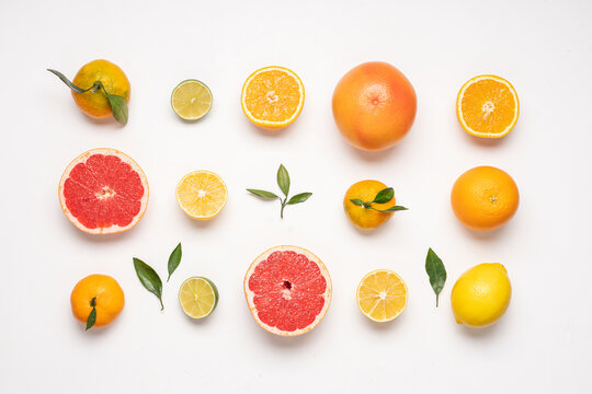 Creative neatly arranged food layout of citrus fruits and leaves on white background.  Flat lay juicy fruits concept