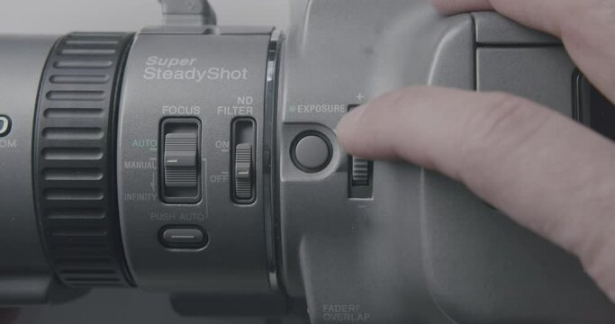 Pressing buttons on an old MiniDV Camcorder. Caucasian hands using an old camera. Static shot with white solid background.