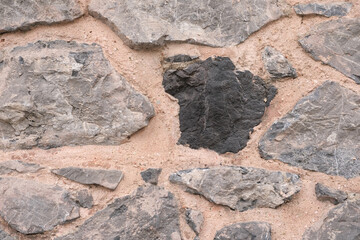 Surface of wall of pink clay and large rough stones close-up as background