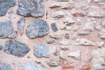 The surface of the wall is made of pink clay and  rough marble and limestone stones