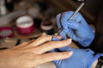 Closeup shot of a woman in a nail salon receiving a manicure by a butician - obrazy, fototapety, plakaty