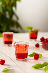 Raspberry alcoholic shots, shot glasses with colored liquor on a white background
