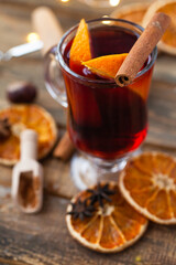 Traditional winter hot drink: mulled wine in glass decorated with orange, spices. Delicious, sweet. Cozy atmosphere, aromatherapy, rustic decor. Romantic christmas eve or new year home party.  Closeup