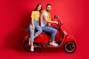 Fototapeta na wymiar young and beautiful caucasian couple on motorcycle isolated on red background, happy man and woman in casual wear enjoy driving, holidays, weekends, happiness