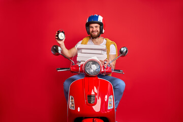 handsome courier guy on motorbike is hurry to deliver orders, check the time, delivery, food, restaurant concept. isolated red background