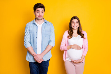 Photo of optimistic young couple stand pregnant woman wear casual outfits isolated on yellow color background