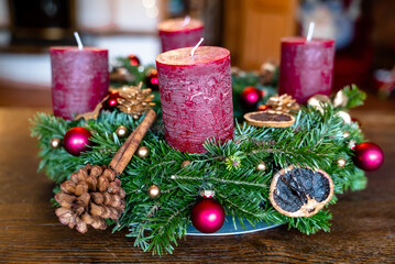 Adventskalender selbst gemacht. Rote Kerzen, Zimt, Kugeln, getrocknete Orangen, Tannenzapfen. Gold