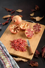 Knife, cut juicy pomegranates, and grains on a wooden board