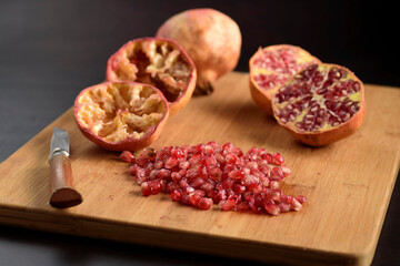 Knife, cut juicy pomegranates, and grains on a wooden board