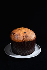 artisanal high italian panettone on a dish and black background whit cutting light